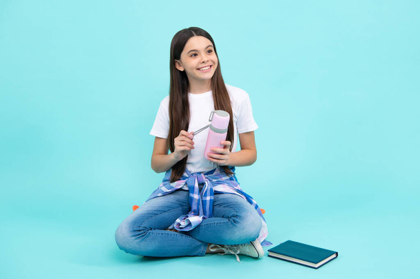 12, 13, 14-jährige Mädchen halten Thermoskanne und Becher mit heißem Tee in der Hand. Glücklicher Teenager, positive und lächelnde Gefühle eines Teenie-Mädchens - Foto, Bild