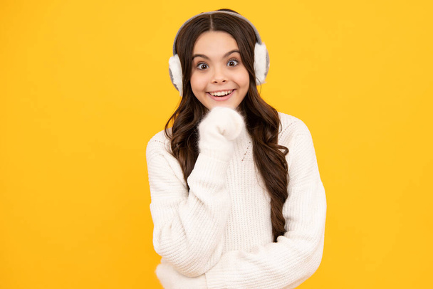 Modern teenage girl 12, 13, 14 year old wearing sweater and winter warm earmuff ear-flaps hat on isolated yellow background - Photo, image
