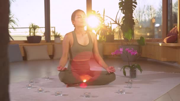 SLOW MOTION: Mooie Aziatische vrouw mediteren en diep ademhalen in lotus pose. Het uitvoeren van mudra 's om de prana stroom te stimuleren. Vrouwelijke persoon intensiveert levensenergie terwijl meditatie in lotus poseren. - Video