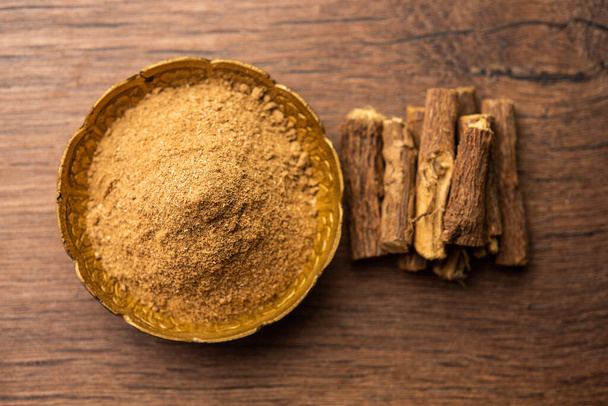 Ayurvedic Mulethi or Liquorice root stick or jeshthamadh powder served in a bowl over moody background - Photo, Image