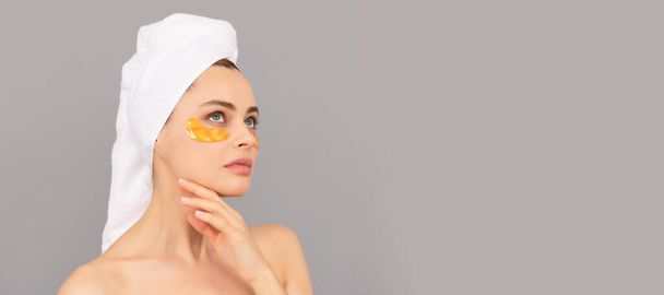beautiful girl with terry towel use facial golden eye patch for skin, beauty. Beautiful woman isolated face portrait, banner with mock up copy space - Foto, imagen