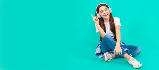 happy teen girl listen to music in wireless headphones. Child portrait with headphones, horizontal poster. Girl listening to music, banner with copy space - 写真・画像