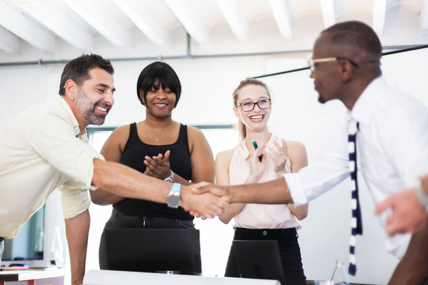 Multiracial business people working together at boardroom table at office. Successful team of colleagues shaking hands and giving applause. - Foto, Imagen