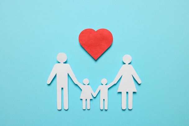 Paper family figures and red heart on light blue background, flat lay. Insurance concept - Foto, imagen