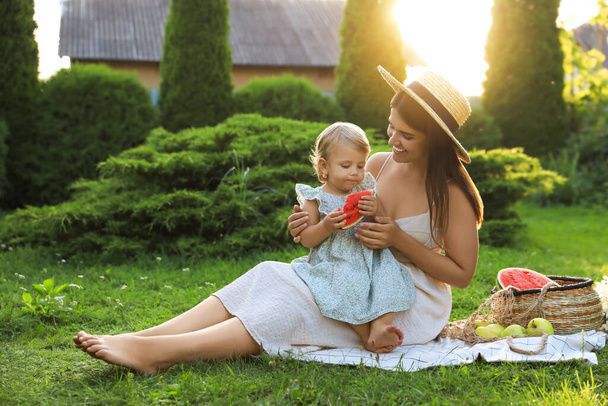 Mother with her baby daughter having picnic in garden on sunny day - Zdjęcie, obraz