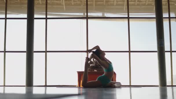 Женщина практикует упражнения йоги для повышения гибкости спины - широкий выстрел - 4K Горизонтальное видео - Кадры, видео