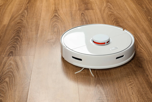 Robotic vacuum cleaner on wooden floor, space for text - Zdjęcie, obraz