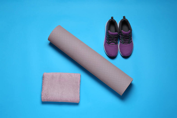 Exercise mat, towel and shoes on turquoise background, flat lay - Fotó, kép