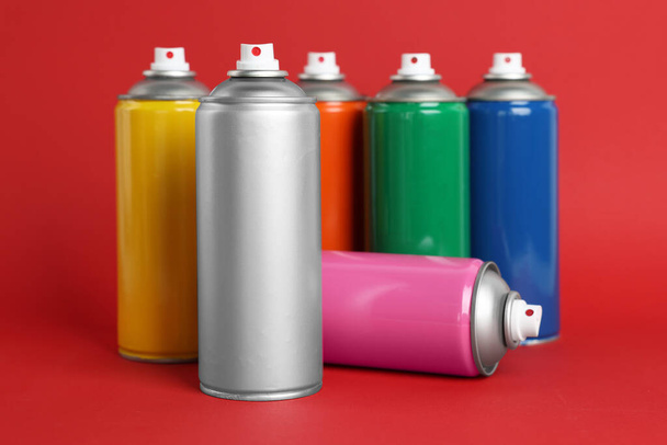 Colorful cans of spray paints on red background - Foto, Imagem