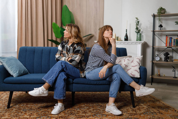 Offended mother and daughter sitting back to back on the sofa - Foto, Imagen