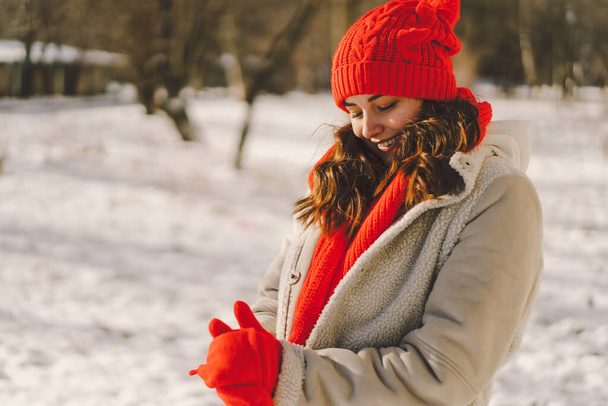 Μια όμορφη γυναίκα με χειμωνιάτικα ρούχα απολαμβάνει τον χειμώνα. Χριστούγεννα και Πρωτοχρονιά έννοια εορτασμού. - Φωτογραφία, εικόνα