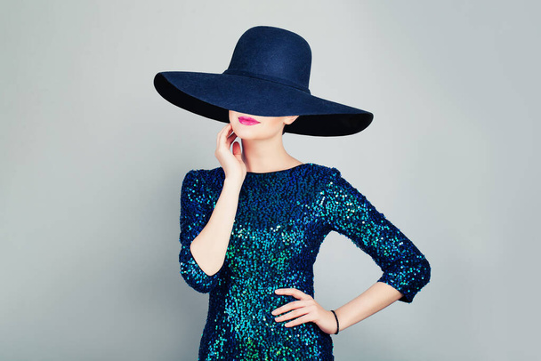 Czarująca kobieta w błyszczącej sukience modnej i szerokim kapeluszu z rondem - Zdjęcie, obraz