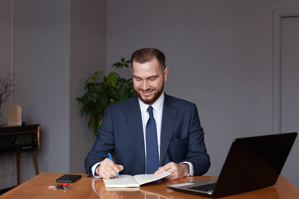 スーツを着た幸せなビジネスマンは彼の仕事についてメモを書いている。マルチタスクコンセプト - 写真・画像