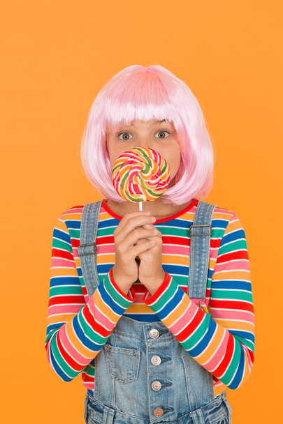 Anime convention. Sweet life. Anime cosplay party concept. Happy little girl. Anime fan. Vibrant character fantastical themes. Modern childhood. Kid with artificial hairstyle eating lollipop. - Foto, Imagem