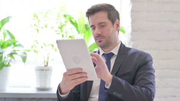 Νεαρός ενήλικος επιχειρηματίας που χρησιμοποιεί ψηφιακή ταμπλέτα στο γραφείο - Πλάνα, βίντεο