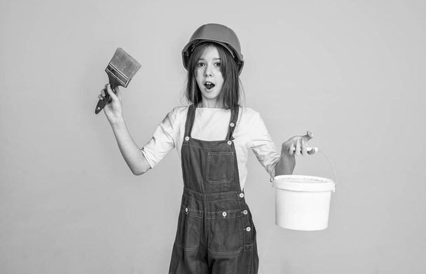 laborer kid wear safety hardhat. labor day. teen girl in uniform and helmet. female builder in hard hat. building and construction. child architect worker. engineer use painting brush and bucket. - Valokuva, kuva
