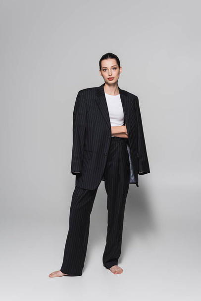 Full length of barefoot model in suit posing on grey background  - Photo, Image