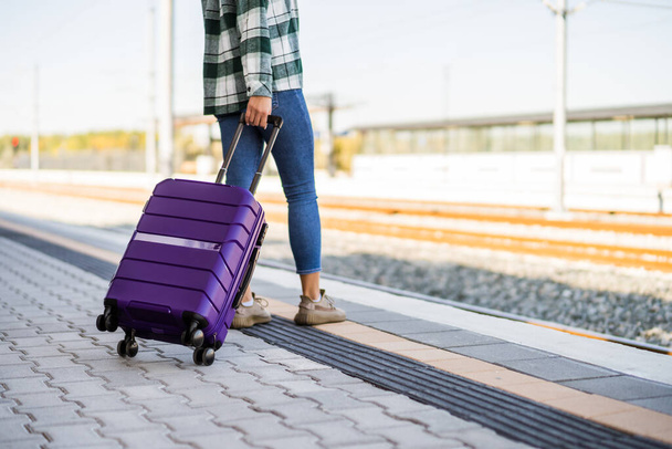 Woman with suitcase standing on train station. - Foto, afbeelding