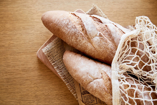 French freshly baked baguettes in eco-shopping bag on rustic sacling - traditional bakery. Top view food. - Photo, Image