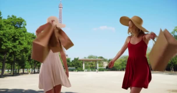 Para podekscytowanych białych kobiet na wakacjach w Paryżu tańczących z radością w pobliżu Wieży Eiffla. Kilka zabawnych młodych pań kręcących się wokół podczas zakupów i zwiedzania Paryża. 4k - Materiał filmowy, wideo