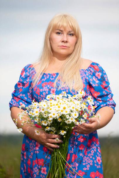Mulher bonita plus size com cabelo branco em um vestido de verão posando ao ar livre com margaridas. Gordinha menina em um prado com flores. - Foto, Imagem