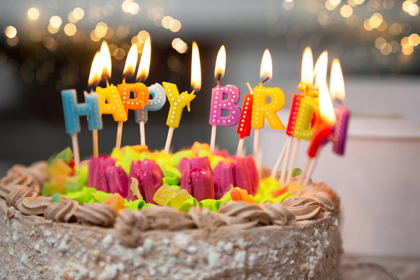 幸せな誕生日のろうそくは、黄金のボケの背景にケーキの上に点灯します. - 写真・画像