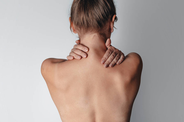 Naked female back. Women's hands wrap around neck. Rear view. - Foto, afbeelding
