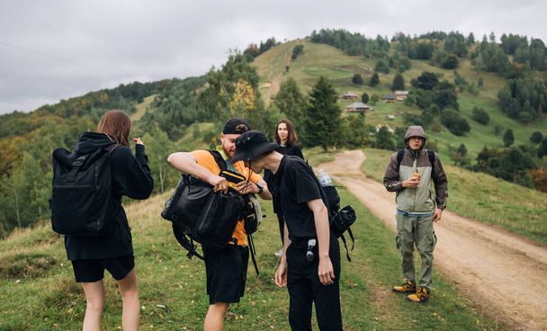 Groupe d'amis randonneurs féminins et masculins debout dans les montagnes sur un sentier pendant l'escalade et le repos, une pause dans les montagnes pendant une randonnée - Photo, image