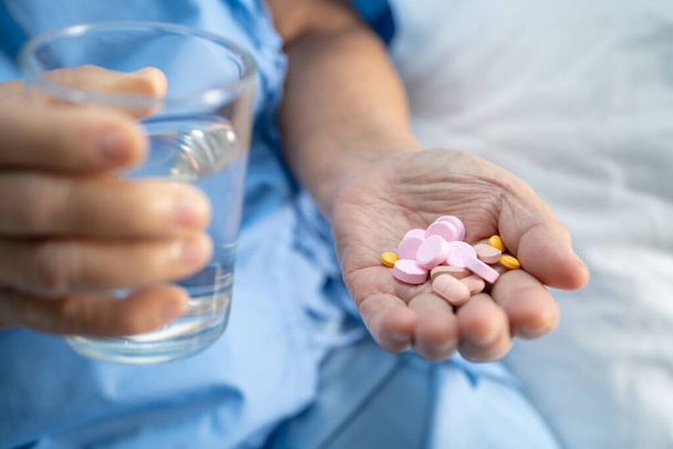 Asian senior elderly old lady woman holding Vitamin pills drug in her hand, healthy strong medical concept. - Photo, image
