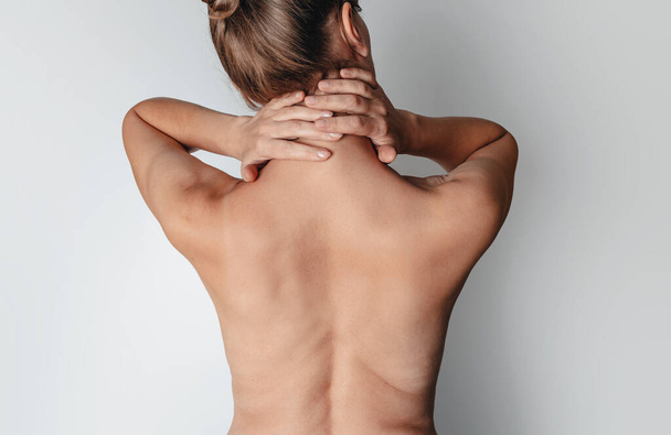 Espalda femenina desnuda. Las manos femeninas detrás de la cabeza. Vista trasera - Foto, Imagen
