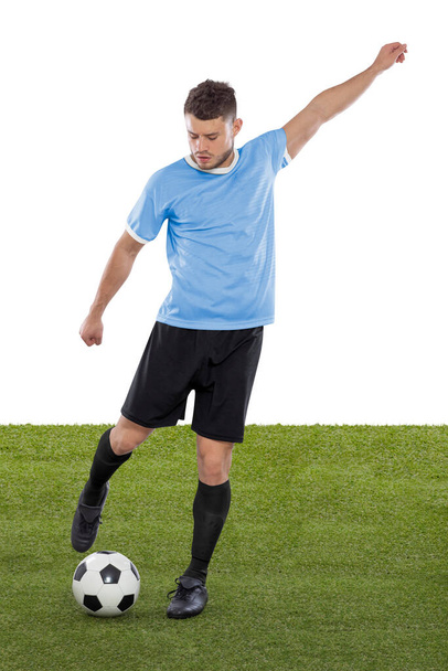 Professional soccer player with light blue Uruguay national team jersey about to score a goal with an expression of challenge and decision on his face on white background. - Photo, image