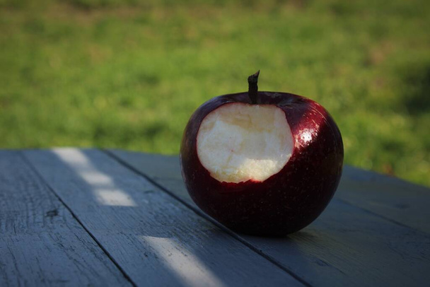 Кусатое яблоко на деревянной доске - Фото, изображение
