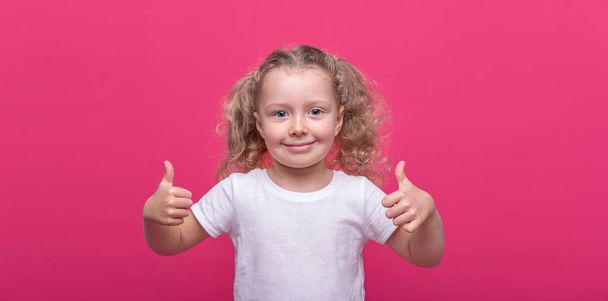 Little cheerful girl on a pink background. - Valokuva, kuva