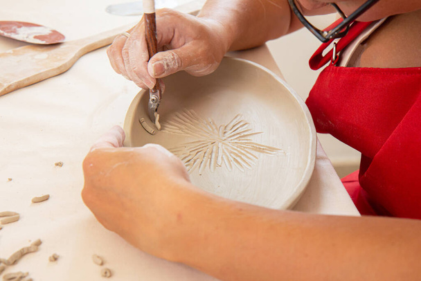 Žena hrnčíř držet hůl a dělat ozdoby na hliněné nádobí. Clay Master vstřikování jílu produkt. Koncept keramického umění a hobby - Fotografie, Obrázek