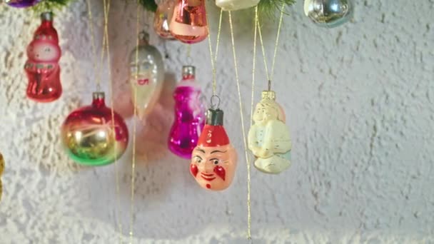 Glazen bal met ruitjes hangend aan een tak op nieuwjaarsavond. Vintage speelgoed op de kerstboom. Close-up decoratie voor een feestelijke avond. Gekleurde lichten flikkeren op de achtergrond. - Video