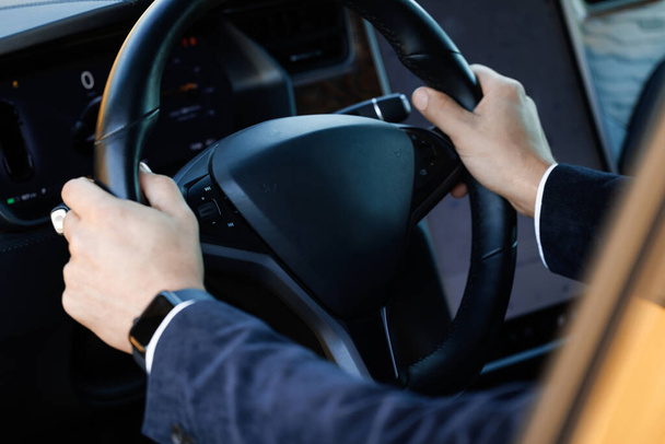 Close up of man hand on vehicle steering wheel as he is driving. Male driving a car in the highway, hands move on the wheel. Unrecognizable businessman putting his hands on steering wheel of car. - Photo, image