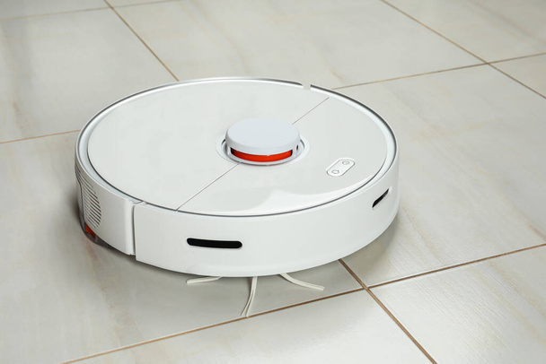 Robotic vacuum cleaner on white tiled floor - Foto, afbeelding