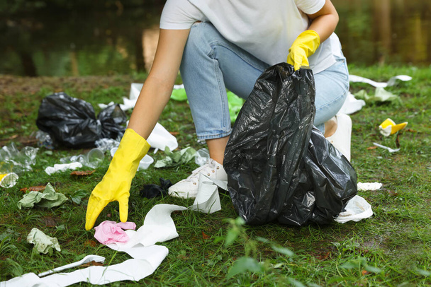 Woman with plastic bag collecting garbage in park, closeup - Fotó, kép