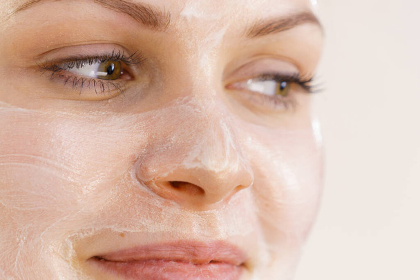 Young woman with cream cosmetic, mask moisture on her face. Beauty treatment. Skincare. - Photo, Image