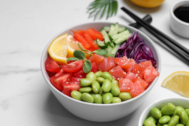 Poke bowl with salmon, edamame beans and vegetables on white marble table - Zdjęcie, obraz