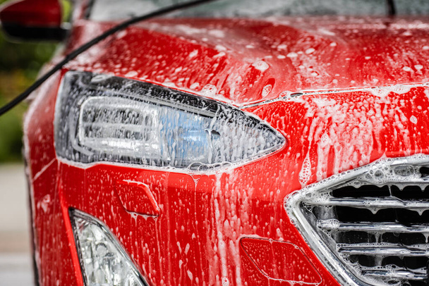 Πλύσιμο και καθαρισμός ενός κόκκινου αυτοκινήτου. - Φωτογραφία, εικόνα