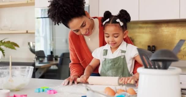 Matka, dziewczyna ucząca się pieczenia w kuchni i ciasto kwiatowe na ladzie gotować ciasteczka dla zabawy, nauki i rozwoju. Szczęśliwa mama, czarne dziecko z uśmiechem i uczy córkę piec razem. - Materiał filmowy, wideo