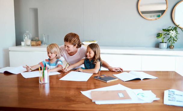 Toda mãe é a primeira professora dos filhos. uma jovem mãe ajudando seus dois filhos pequenos com seus trabalhos de casa em casa - Foto, Imagem