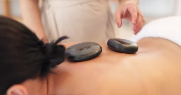 Hands, massage therapist or hot stone in spa, salon or healthcare retreat in self care, muscle release or stress management. Women, back or zen luxury rocks in calm wellness or relax skincare therapy. - Footage, Video