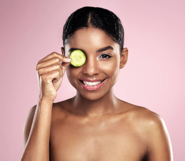 Les concombres peuvent être utilisés pour toutes sortes de problèmes de peau. une belle jeune femme posant avec une tranche de concombre - Photo, image