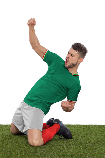 Professional soccer player with a green Mexico national team jersey shouting with excitement for scoring a goal with an expression of challenge and happiness on a white background. - Photo, image