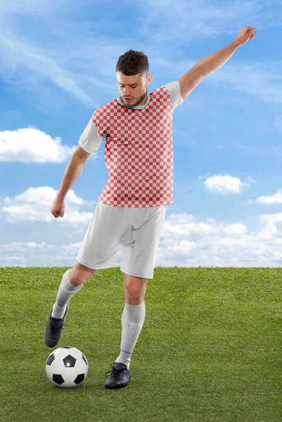 Professional soccer player with red and white Croatia national team jersey about to score a goal with an expression of challenge and decision on his face on field grass and cloud background - Φωτογραφία, εικόνα