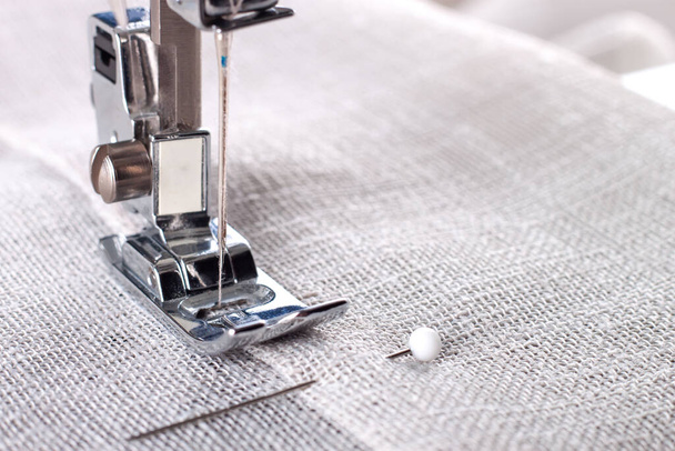 Modern sewing machine presser foot with linen fabric and thread, closeup, copy space. Sewing process clothes, curtains, upholstery. Business, hobby, handmade, zero waste, recycling, repair concept - Φωτογραφία, εικόνα