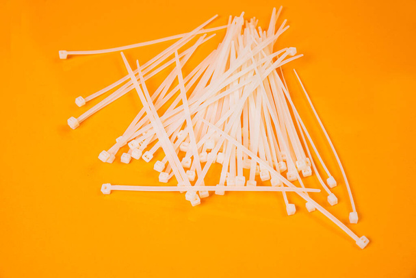 nylon cable ties in glass in jar in bucket on orange background front top view isolated - Photo, Image