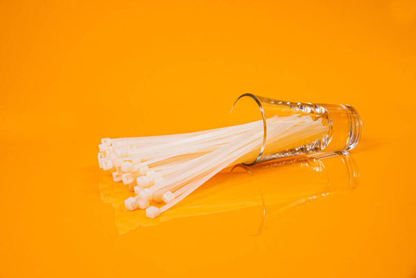 laços de cabo de nylon em vidro em frasco em balde no fundo laranja frente vista superior isolado - Foto, Imagem